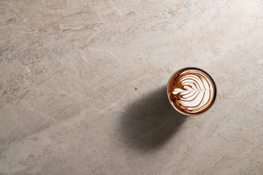 A warm milk drink in a glass, seen from above on a pale stone surface