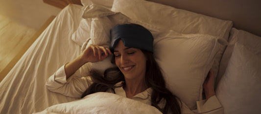 Woman resting in bed wearing the Sweet Bee Deep Sleep Mask in warm evening light