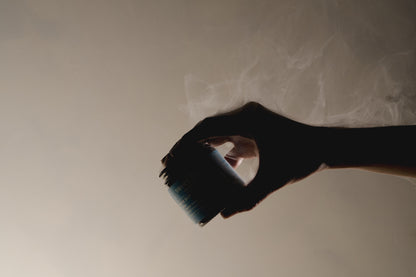 A hand holding the Breathe Deep Cloud Balm jar in soft vapour