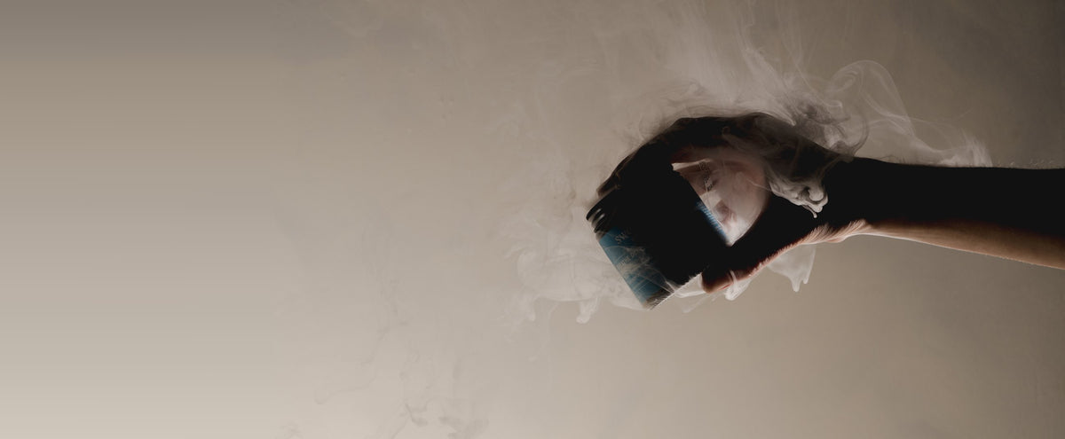 A hand holding the open Breathe Deep Cloud Balm jar with vapor rising